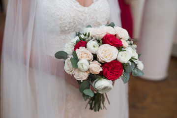 Gorgeous wedding bouquet of red and white flowers in bride's hands