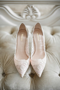 Bride's shoes with laces stand on white sofa