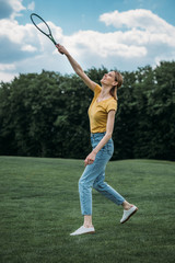 young smiling caucasian woman playing badminton at park