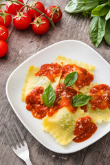 Ravioli with tomato sauce and basil on wooden table

