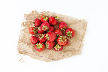 A pile of fresh juicy strawberries lies on an old sackcloth, iso