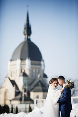 Obraz premium Groom hugs tender bride in fur coat standing outside