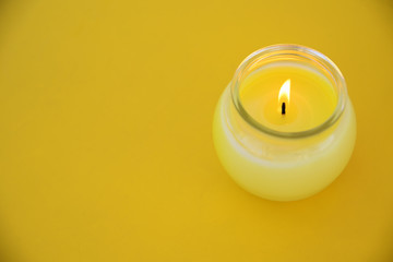 Yellow minimalistic centerpiece with a citronella candle in a glass. Empty copy space for Editor's text.