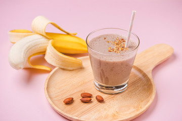 Fresh made banana smoothie in a glass on pink background