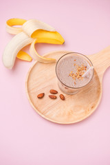 Fototapeta na wymiar Fresh made banana smoothie in a glass on pink background