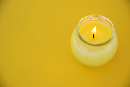Yellow minimalistic centerpiece with a citronella candle in a glass. Empty copy space for Editor's text.