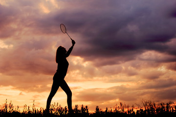 Silhouette badminton girl on sunset.