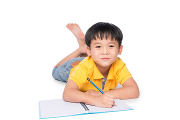 Schoolboy lying down and writing in notebook.