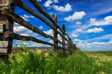 Picture of a fence of logs in a village with a landscape