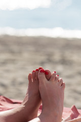 Holiday concept. Woman feet close-up relaxing on beach, enjoying sun and splendid view. Woman tanned legs on sand beach. Travel concept. Happy feet in tropical paradise