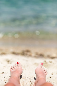 Holiday concept. Woman feet close-up relaxing on beach, enjoying sun and splendid view. Woman tanned legs on sand beach. Travel concept. Happy feet in tropical paradise