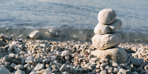 Fototapeta na wymiar Pile of pebble stones over blue sea in the background