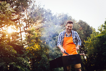 Handsome man preparing barbecue outdoors for friends