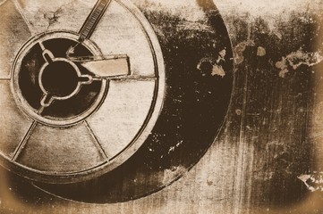 Old sepia film reel on a scratched and rusty metal background.