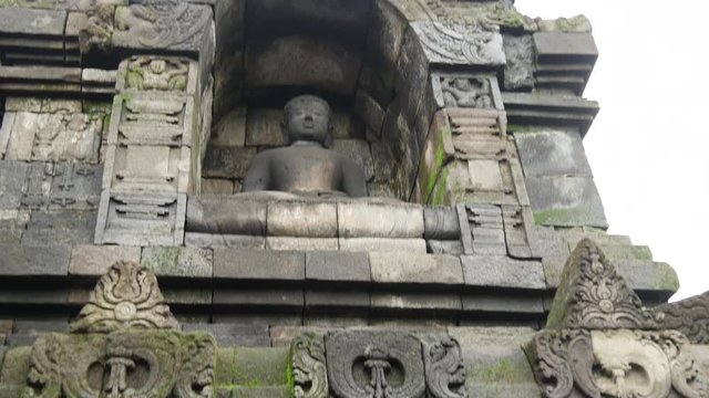 Tilt down from a buddha statue at the Borobudur a 9th-century Mahayana Buddhist Temple in Magelang, Central Java, Indonesia