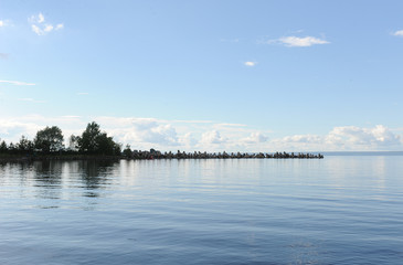 Water landscape on a summer clear day. Blue sky, clouds. Islands far away