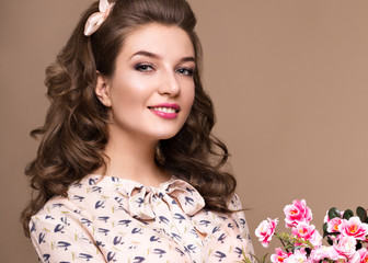 Fototapeta premium Fresh young girl in a light silk dress, smile, retro curls in the style of pin-up with a basket of flowers in her hands. Beauty face and body. Photos shot in studio
