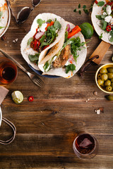 Tacos with fried avocados , tomatoes and greens on distressed wooden background. Served with beer, lime and olives. Mexican cuisine interpretation. Vertical framed composition with text space.