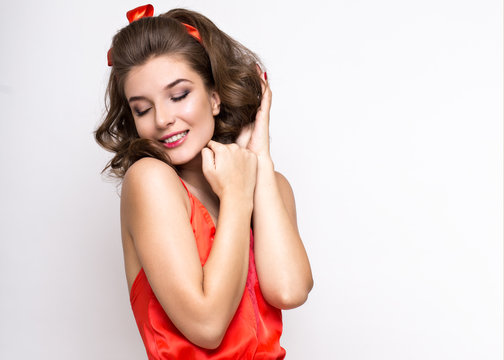 Young fresh girl in red silk pajamas, smile and curls retro pin-up style. Beauty face and body. Photos shot in studio