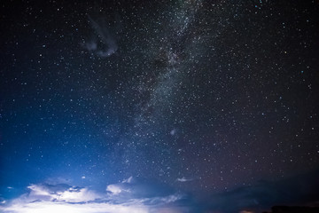 Night sky during thunderstorm in the distance with milky way and stars