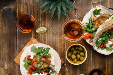 Tacos with fried avocados , tomatoes and greens on distressed wooden background. Served with beer, lime and olives. Mexican cuisine interpretation