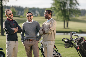 Happy multiethnic golfers spending time together in golf course