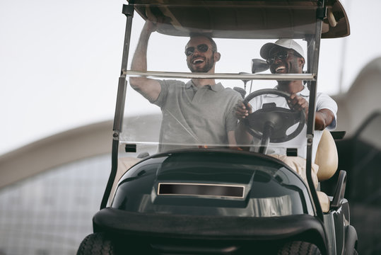 adult multiethnic friends having fun while driving golf cart
