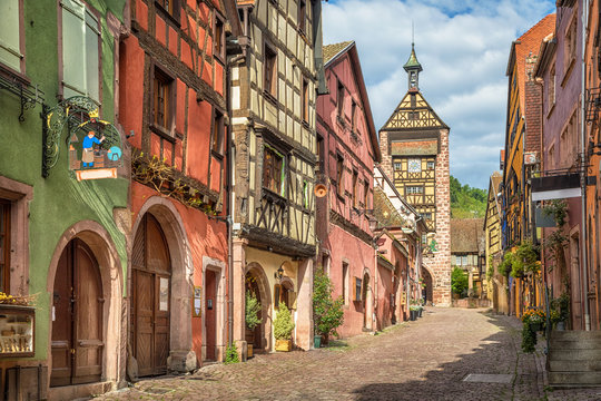Fototapeta Central street of Riquewihr village with colorful traditional half-timbered french houses and Dolder Tower, Alsace, France