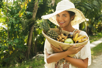 Beautiful woman wearing broad-brim hat in the tropical garden