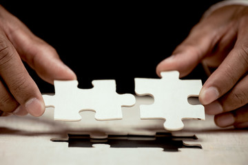 Businessman hand put the last piece of jigsaw puzzle to complete the mission. Business success, solutions and strategy concept