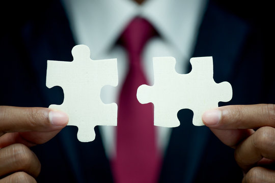 Businessman try to connect two piece of jigsaw puzzle. Business success, solutions and strategy concept