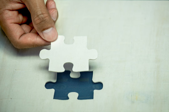 Businessman hand put the last piece of jigsaw puzzle to complete the mission. Business success, solutions and strategy concept,vintage color tone