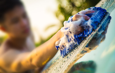 Hands hold blue sponge for washing car.