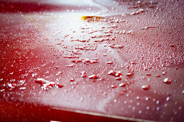 Detail of water drops on a red car after the rain