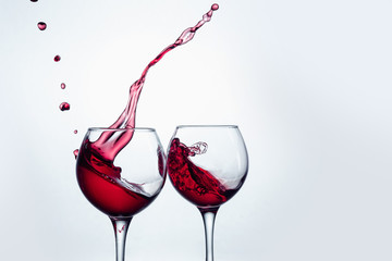 Two wine glasses in toasting gesture with big splashing.