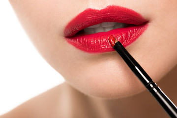 Cropped shot of woman applying red lipstick with brush