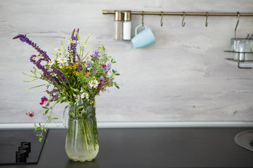 Kitchen in the style of Provence. On the table is a vase with wild flowers.