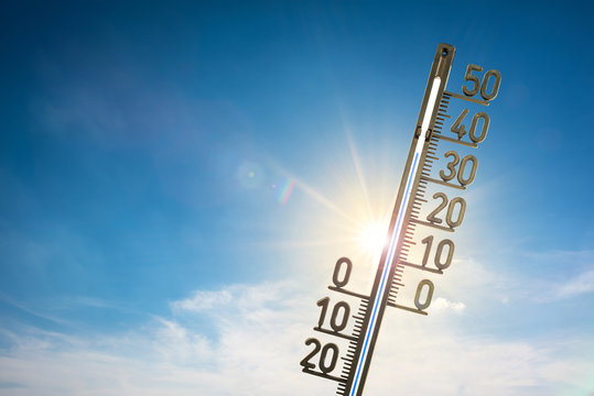 Thermometer mit strahlender Sonne und blauem Himmel im Hintergrund