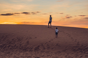 Father and son at the red desert at dawn. Traveling with children concept