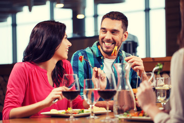 happy couple with friends eating at restaurant