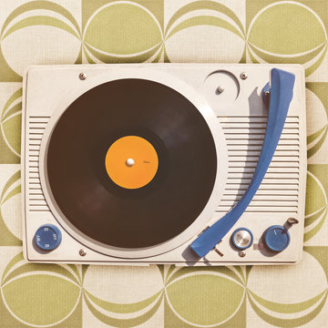 Vintage vinyl turntable player on retro wallpaper