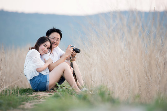 Beautiful young dating couple in city taking photos on park during sunset time
