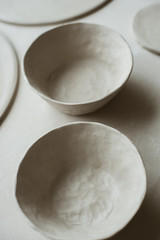 Ceramic raw grey plates made by talented hands of ceramist on table in workshop studio.