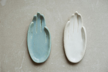 Top view on chamotte clay blue and white hands for holding rings and little things on grey industrial table