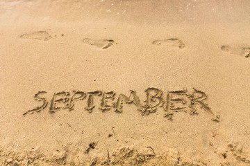 Inscription on wet sand september
beach.