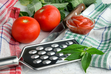 Tomatoes, greens, grater for preparation of tomato paste or ketchup concept of cooking