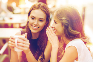 young women drinking coffee and talking at cafe