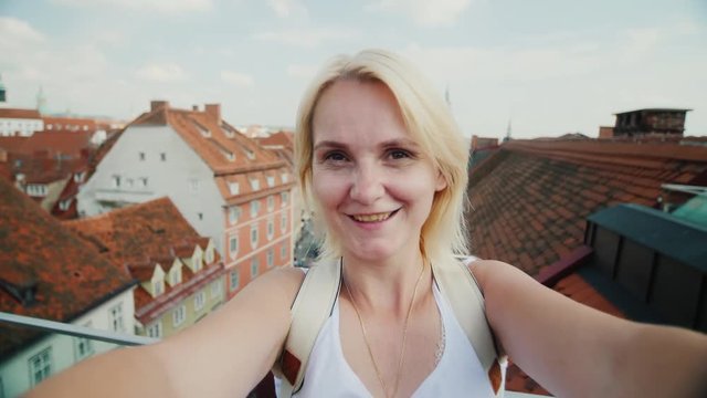 A young woman shoots herself in the video on the background of the old European city of Graz in Austria. Looks at the camera, smiling