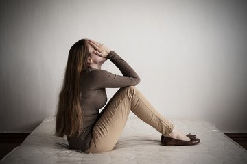 Depressed woman sitting on a mattress