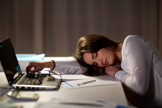 tired woman sleeping on office table at night